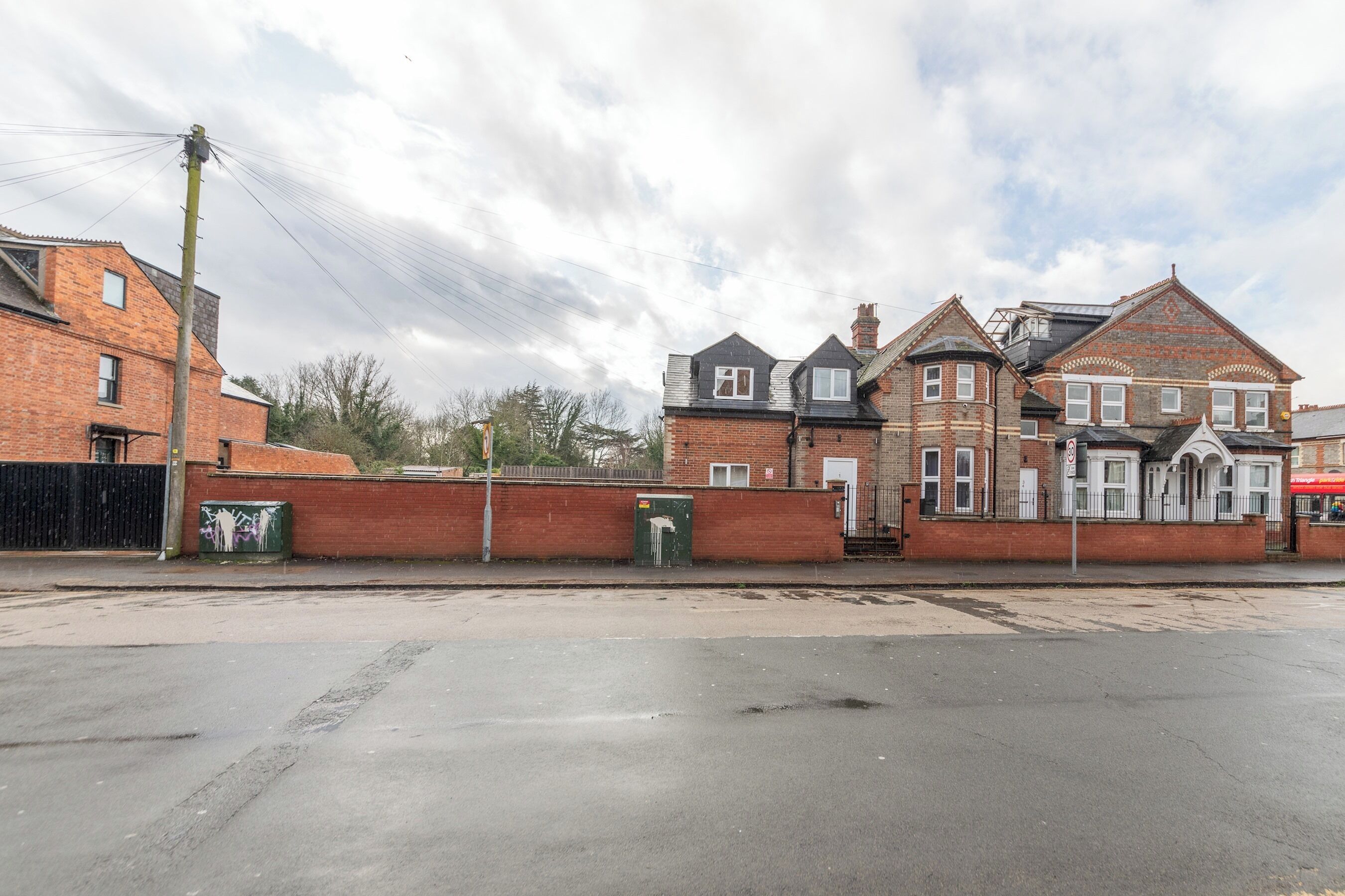 A street view with a row of brick houses, a clear sky, and a pedestrian crossing.