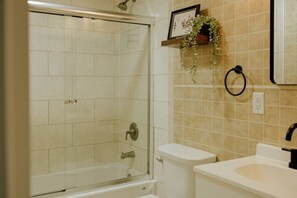 Un baño con ducha envuelta en vidrio, inodoro y lavamanos.