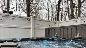 Ein Whirlpoolbereich mit weißem Zaun, Bäumen im Hintergrund und blauem Himmel.