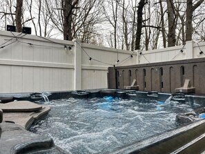 A hot tub area with a white fence, trees in the background, and a clear sky. - Fox Hollow Retreat | Sleeps 11 |Family Friendly (Emerald Lakes)