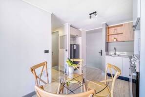 A modern kitchen with white cabinets, a built-in oven, and a wooden shelf. - Urban Essence - 2D Santiago (Santiago)