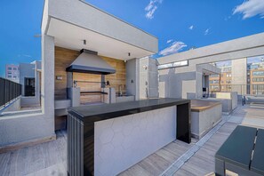 A modern outdoor kitchen area with a built-in grill, a sink, and a large countertop. - Urban Essence - 2D Santiago (Santiago)