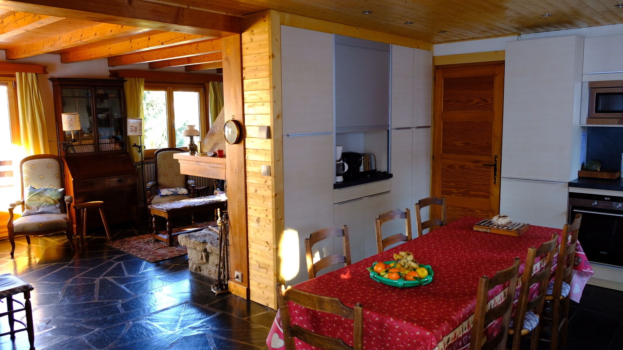 Ein gemütlicher Essbereich mit roter Tischdecke, Holzsesseln und einer Obstschale.