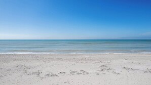 Uma praia com céu claro e mar calmo.