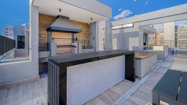 A modern outdoor kitchen area with a built-in grill, a sink, and a large countertop. - Nomad Stay  Pool, Wifi near La Moneda (Santiago)