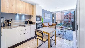 A modern kitchen with white cabinets, a dining area with a table and chairs, and a balcony with a view of buildings. - Nomad Stay  Pool, Wifi near La Moneda (Santiago)