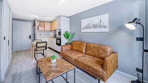 A modern living room with a brown leather sofa, a wooden coffee table, and a cityscape painting on the wall. - Nomad Stay  Pool, Wifi near La Moneda (Santiago)