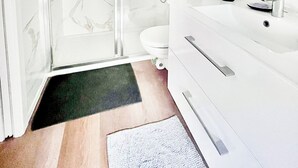 Ein modernes Badezimmer mit Duschkabine aus Glas, einem weißen Waschbecken und einem großen Spiegel.