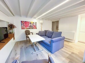 Ein modernes Wohnzimmer mit einem blauen Sofa, einem weißen Couchtisch und einem Bild an der Wand.
