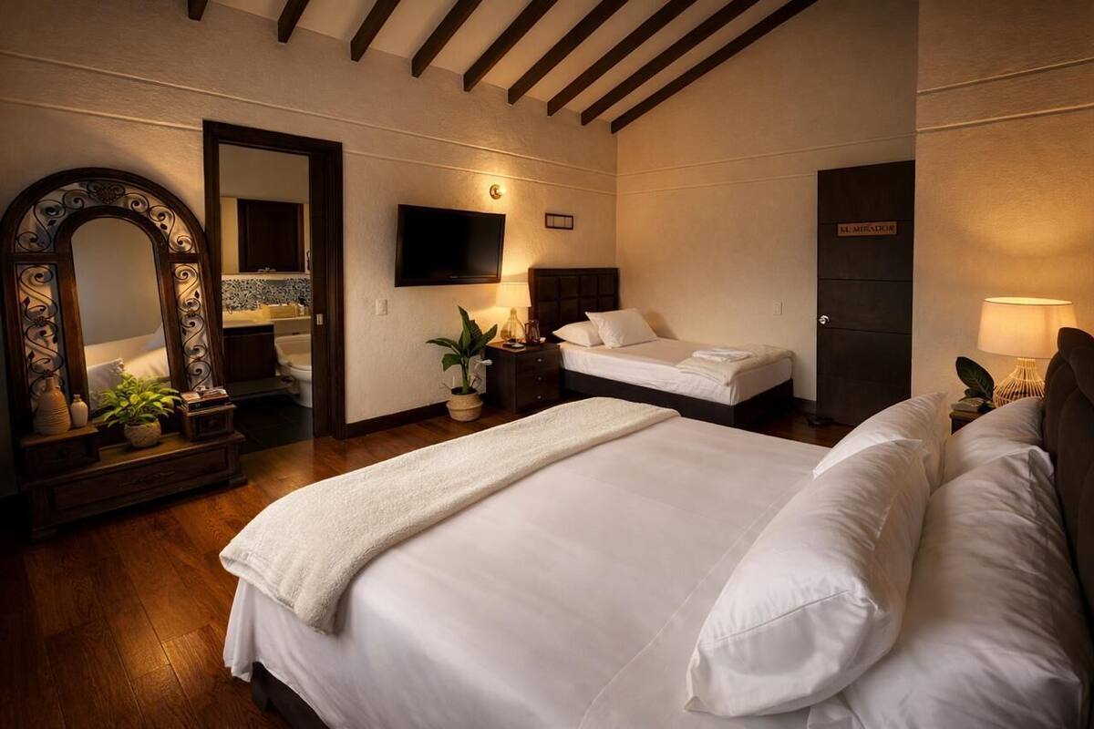 Ein Schlafzimmer mit einem großen Bett, einem Fernseher, einem Spiegel und einer Tür mit der Aufschrift 'EL MIRADOR'.