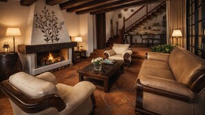 A cozy living room with a fireplace, leather sofas, a coffee table, and a staircase leading to an upper level. - Candelaria Campestre (El Carmen de Viboral)