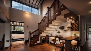 A spacious kitchen with a wooden staircase, a dining area with bar stools, and a view of a vehicle outside. - Candelaria Campestre (El Carmen de Viboral)