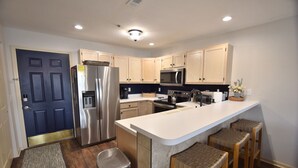 Una cocina moderna con armarios de madera, electrodomésticos de acero inoxidable y una isla central con taburetes.