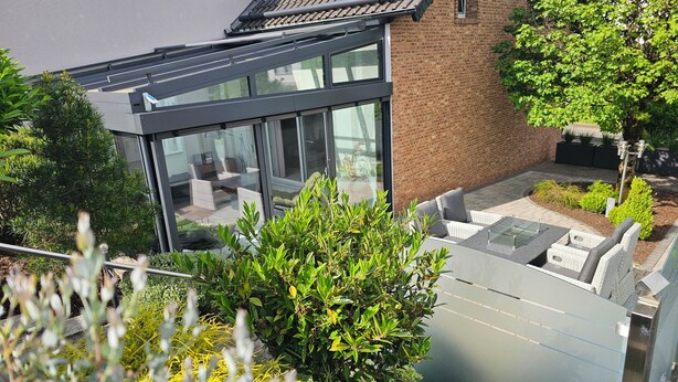 Een modern gebouw met grote ramen, een glazen dak en een bakstenen gevel.