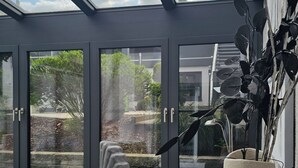 Een conservatorium met een modern ontwerp, met een stenen beeldhouwwerk, een grote vaas en een bank.