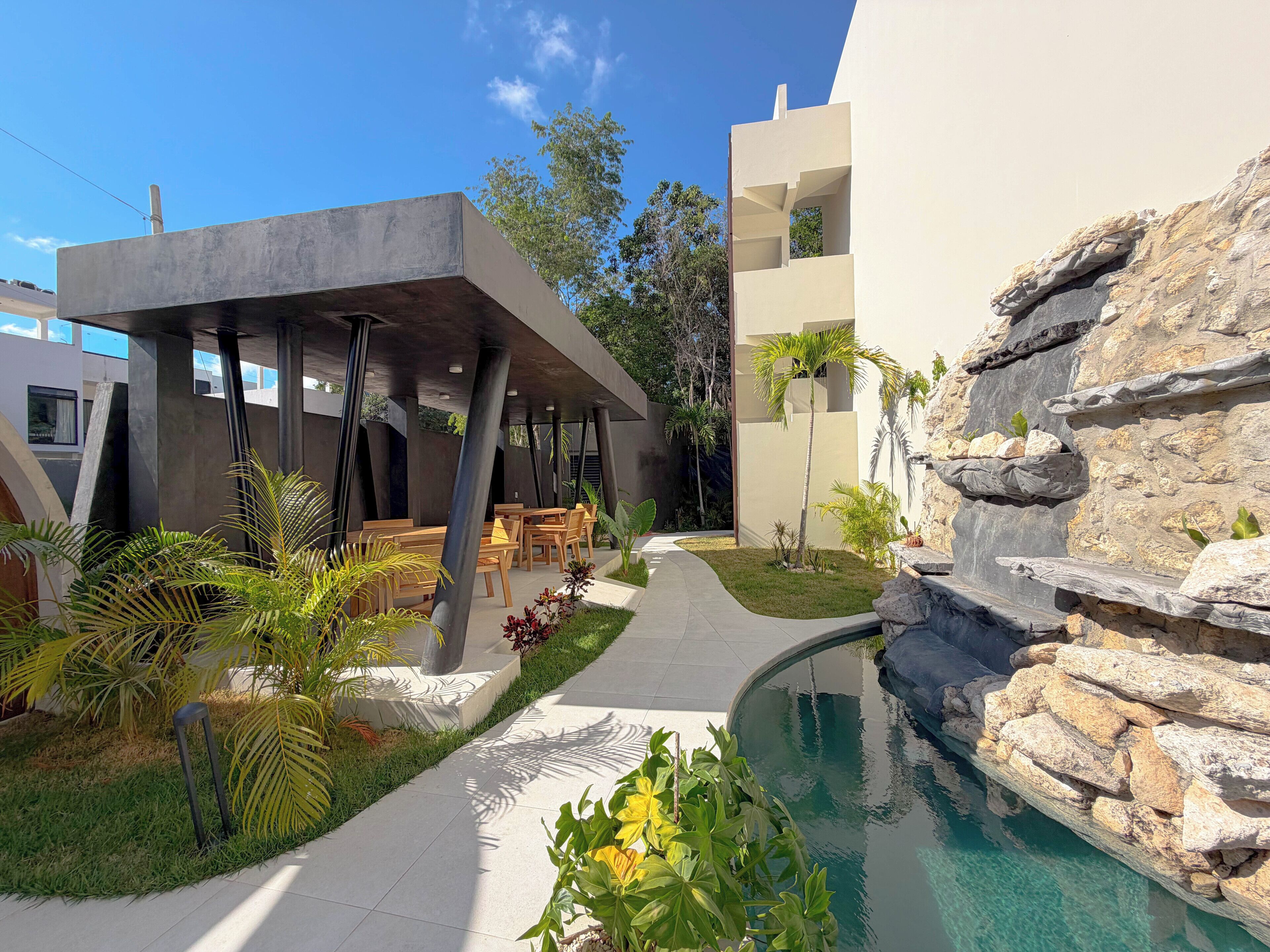 A modern outdoor area with a pool, seating, and a rock feature.