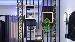 Una habitación moderna con una paleta de colores blanco y negro, que presenta un separador negro con estanterías y una planta colgante.