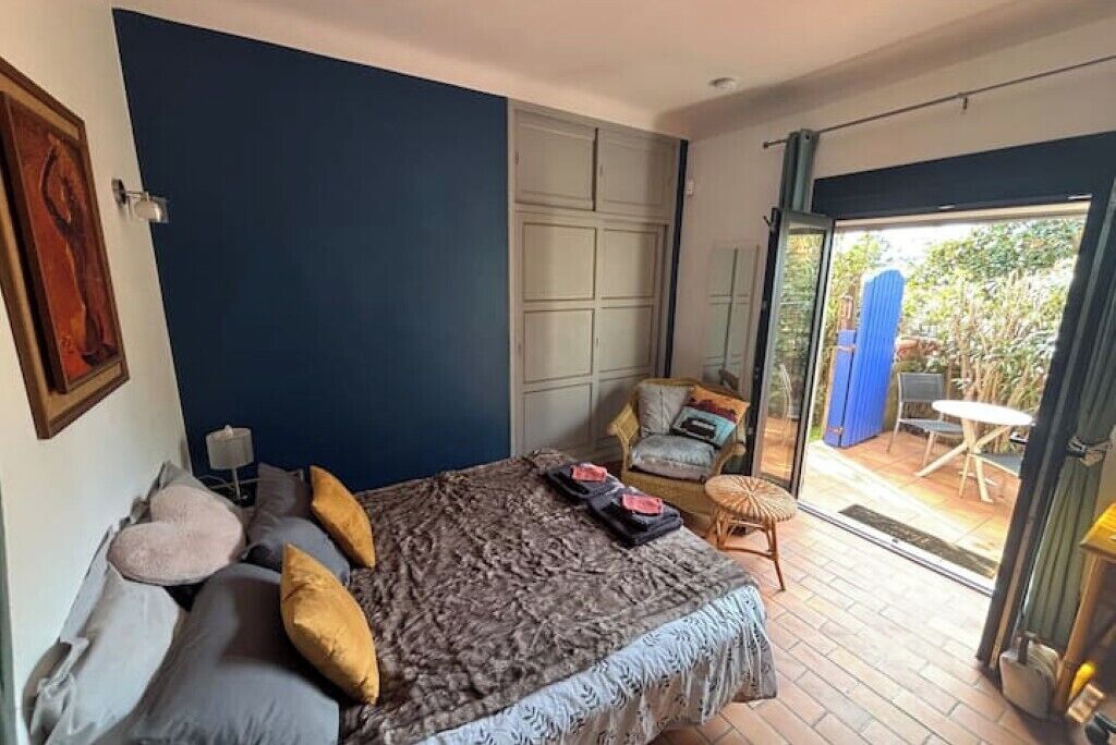 Une chambre avec un grand lit, une porte-fenêtre coulissante donnant sur une terrasse et une chaise près de la porte.