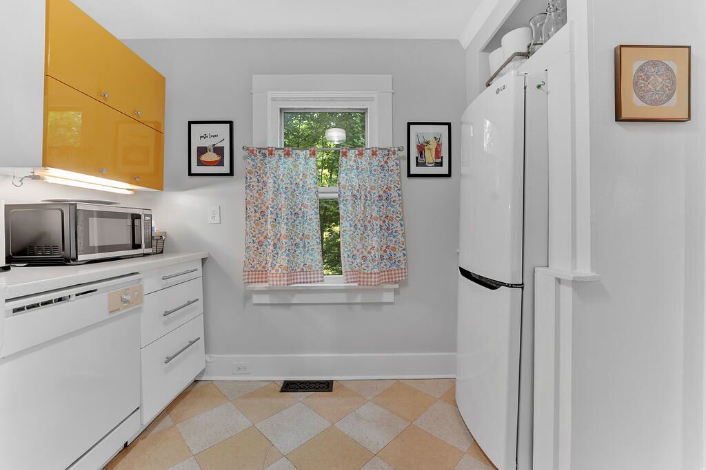 A compact kitchen with white cabinets, a microwave, and a refrigerator.