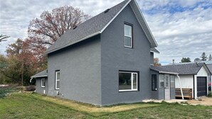 Una casa de dos pisos con fachada gris, techo inclinado y un pequeño jardín delantero.