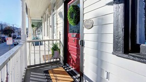 Hotellin sisäänkäynti, jossa on punainen ovi, tervetulomatto ja postilaatikko.
