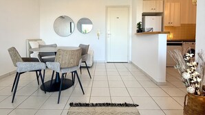 Una sala de estar moderna con comedor, una cocina al fondo y un espejo grande en la pared.