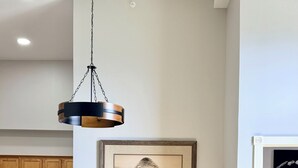 A dining area with two upholstered chairs, a hanging pendant light, a framed picture on the wall, and a kitchen in the background. - Ski In Ski Out Top Floor 2 BR Seneca Corner Unit. Newly Renovated-Garage Parking (Snowshoe)