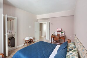 Een slaapkamer met een bed, een bureau, een stoel, een kledingkast en een badkamer.