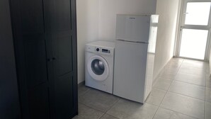 Ein Waschraum mit einer Waschmaschine und einem Kühlschrank.