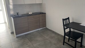 Eine moderne Küche mit dunkler Arbeitsplatte, Holzschränken und einem schwarzen Esstisch mit einem Stuhl.