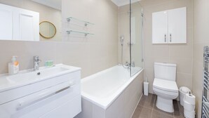 A modern bathroom with a white sink, glass shower enclosure, and a toilet. - Quirky Hampstead Flat RH6 (London)