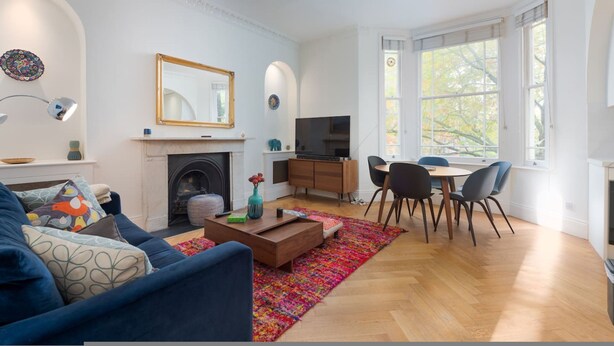 A living room with a fireplace, a television, and a dining area with a table and chairs. - Quirky Hampstead Flat RH6 (London)