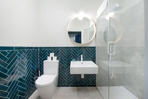 Een moderne badkamer met een wit toilet, een wastafel en een douche.
