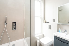 A modern bathroom with a shower, toilet, and sink. - Gorgeous Apartment by the Park SS2 (London)
