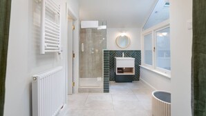 A modern bathroom with a shower, a vanity with a mirror, and a radiator. - Stylish Hyde Park Apartment PS2 (London)