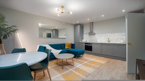 A modern kitchen with grey cabinets, a white countertop, and a stainless steel range hood. - Stylish Hyde Park Apartment PS2 (London)