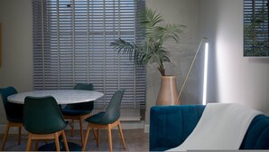 A dining area with a round table, chairs, a potted plant, and a floor lamp. - Stylish Hyde Park Apartment PS2 (London)