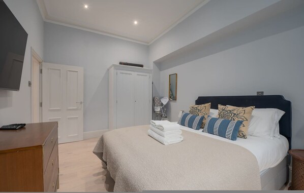 Een slaapkamer met een bed, een kaptafel, een kledingkast en een spiegel.