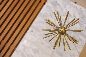 A modern chandelier with a central spherical element and radiating arms, mounted on a marble surface. - Incredible Hyde Park Apartment PS5 (London)