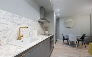 Une cuisine moderne dotée de plans de travail en marbre, d’une hotte en acier inoxydable et d’un coin repas avec une table ronde et des chaises.