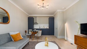 A modern living room with a grey sofa, a white coffee table, and a TV on a wooden cabinet. - Gorgeous Apartment by the Park PS6 (London)