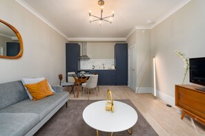 Un salon moderne avec un canapé gris, une table basse blanche et un téléviseur posé sur un meuble en bois.