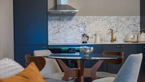 A modern kitchen with dark blue cabinets, a marble backsplash, and a stainless steel range hood. - Gorgeous Apartment by the Park PS6 (London)