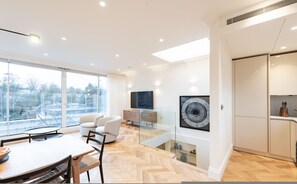 A modern interior with a dining area, a sofa, a TV, and a kitchen. - Beautiful Hampstead Home RH9 (London)