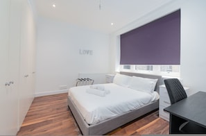 A modern bedroom with a bed, a desk, and a window with a view. - Beautiful London Flat FS3 (London)