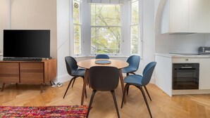 Una cucina moderna con mobili bianchi, forno integrato e una finestra con vista sugli alberi.