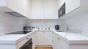 Una cucina moderna con mobili bianchi, un forno a microonde, un tostapane e un bollitore.