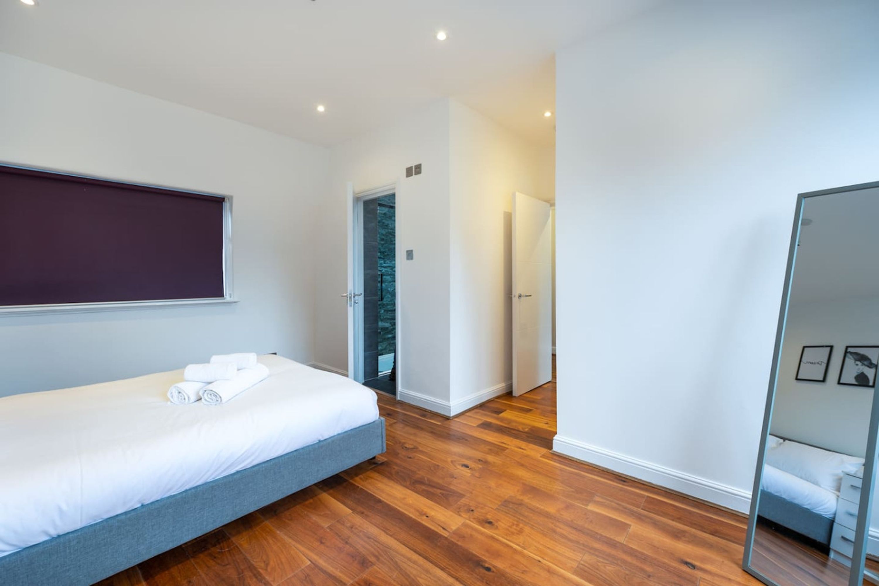 Une chambre à coucher moderne avec un lit, une armoire et un miroir.