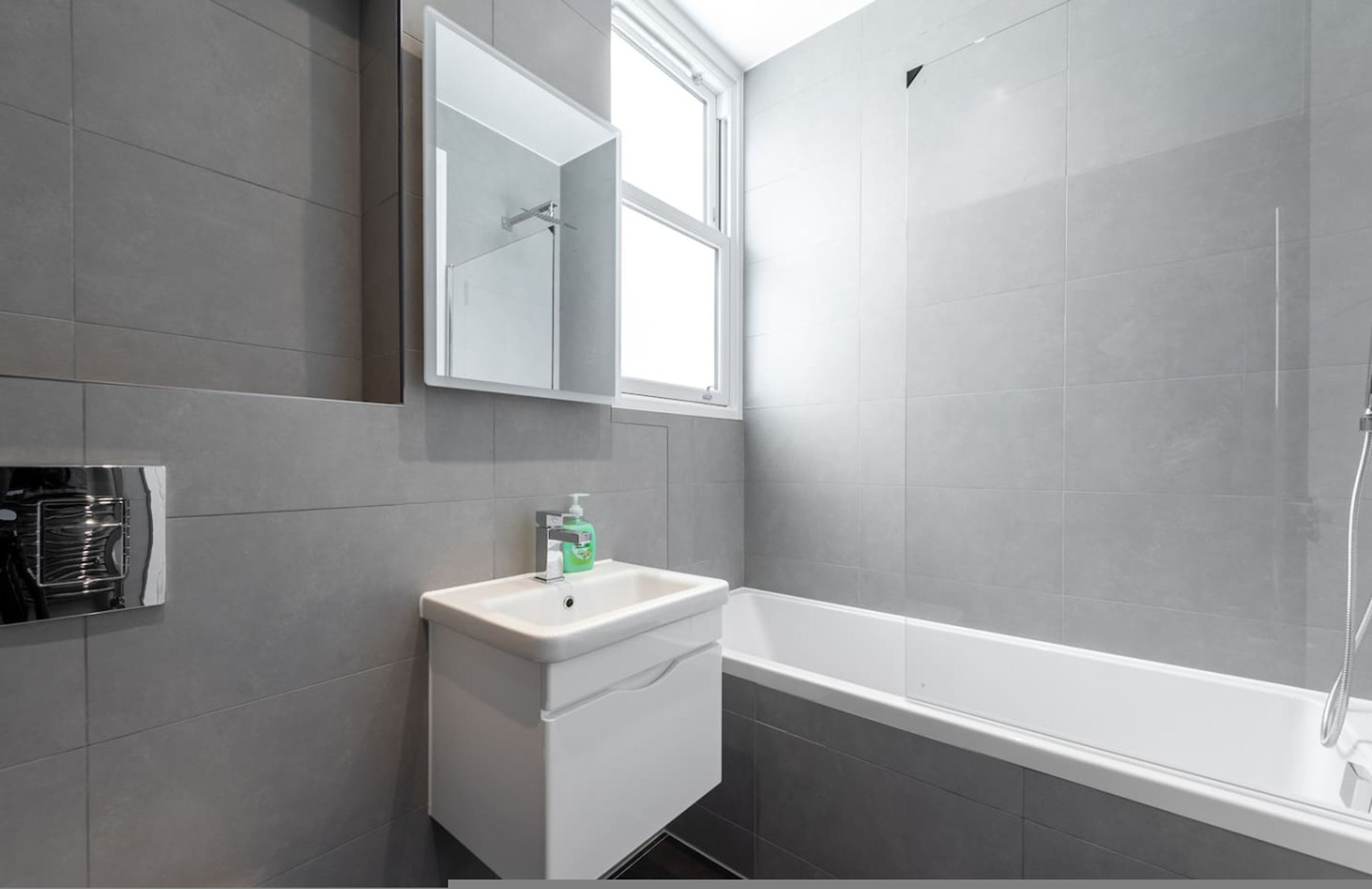 Une salle de bain moderne avec un lavabo blanc, un miroir et une baignoire.