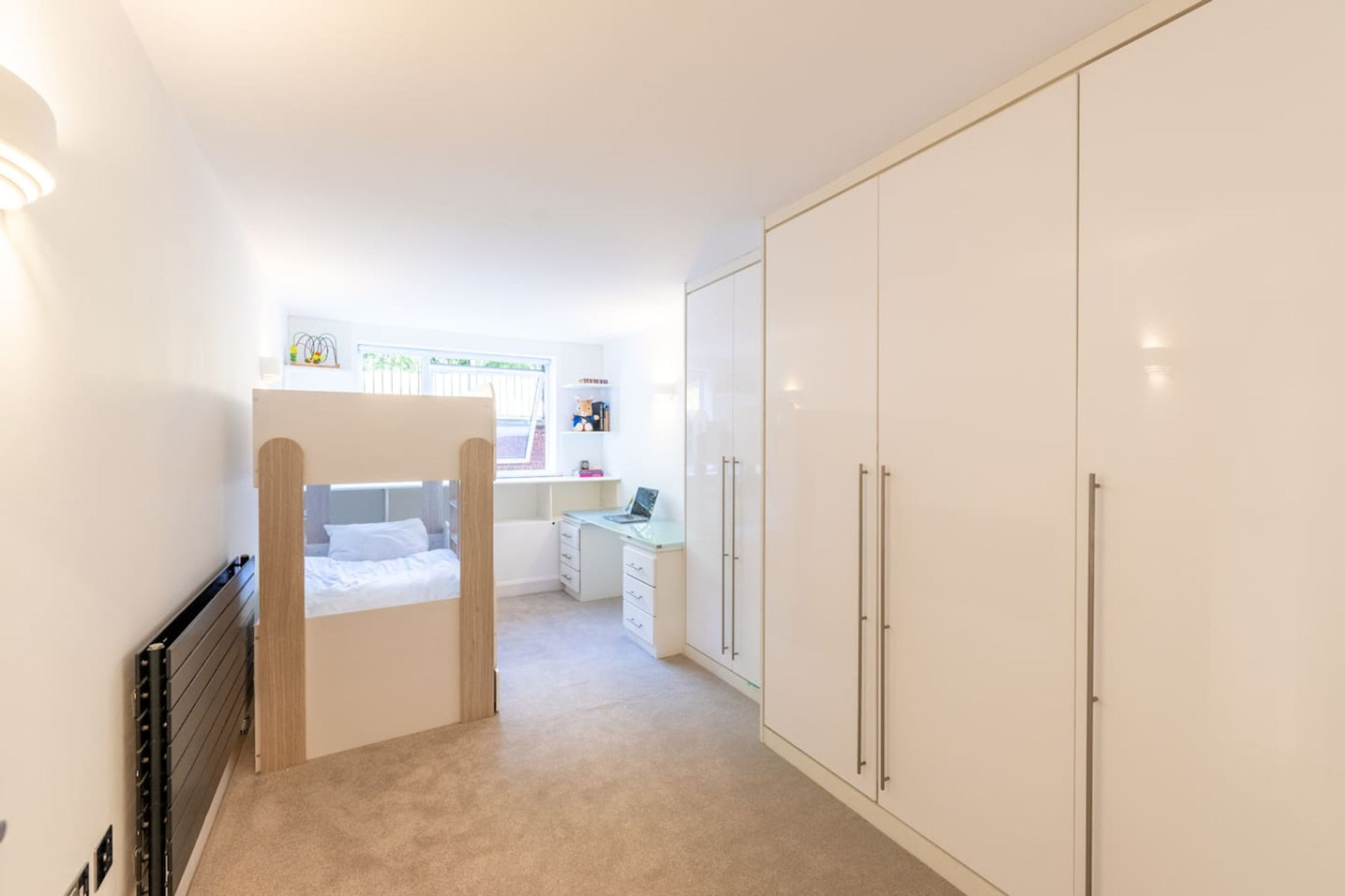 Quarto com uma cama beliche, uma escrivaninha e um guarda-roupa.